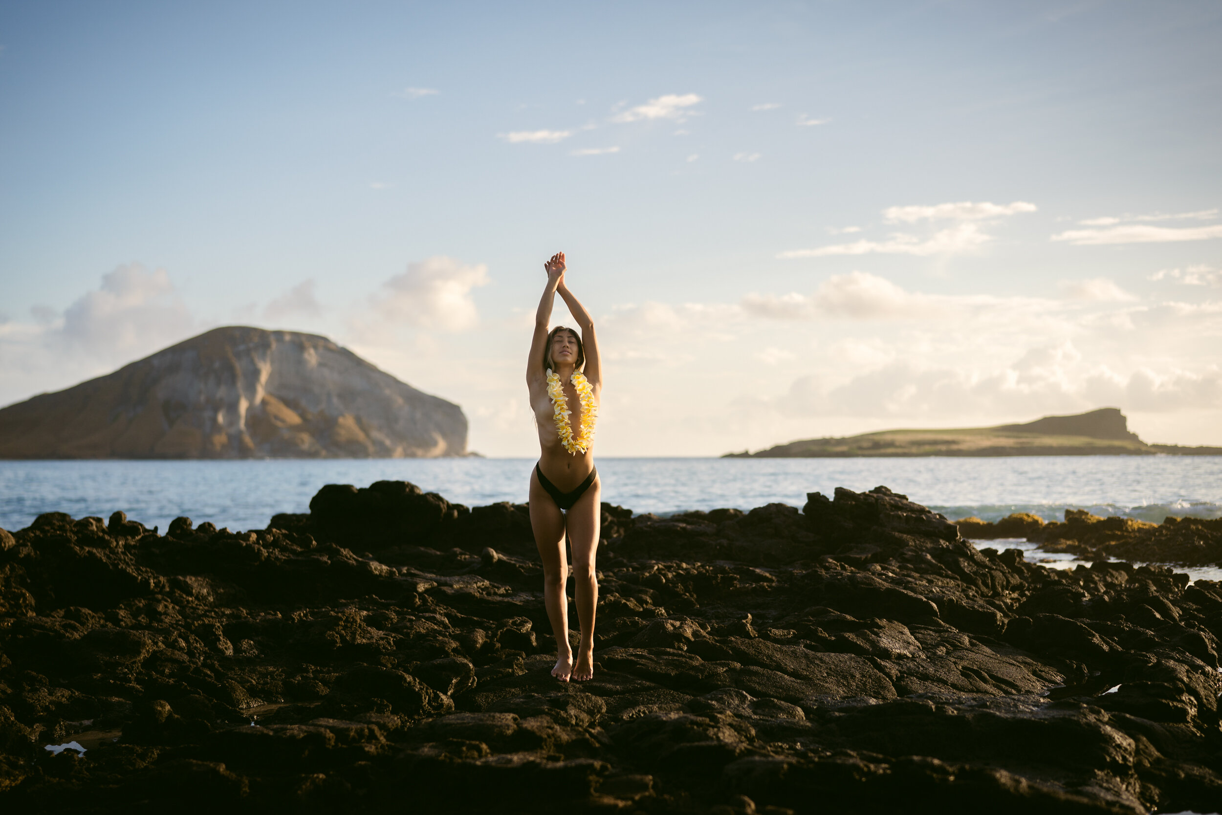 Woman stretching on lava rocks by the ocean near Makapuu, Oahu