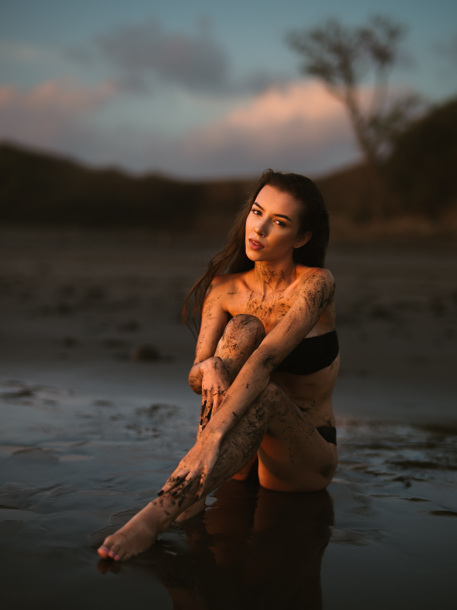 Woman seated on wet sand at dusk — beach portrait by Michael Sasser